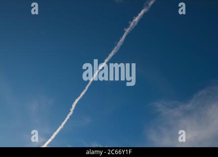 Fast moving clouds during a sunny day in the blue sky with the transition to evening hours along with the occasional flight of the aircraft leaving wh Stock Photo
