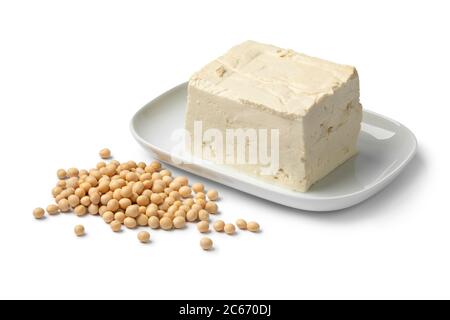 Piece of fresh firm tofu and dried soy beans close up isolated on white background Stock Photo