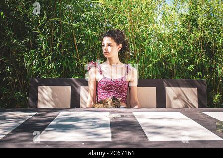 young girl with her cat sitting at the table against bamboo leaves Stock Photo