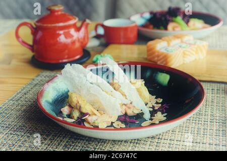 Maki rolls, fried shrimps and tea on table, Japanese cuisine restaurant, toned Stock Photo