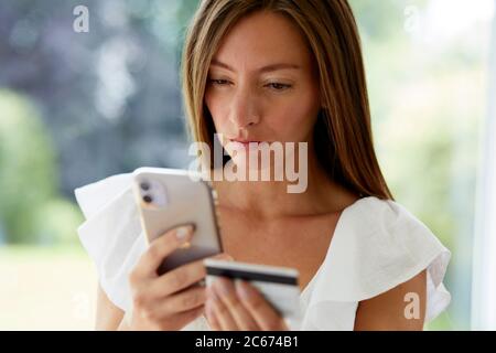 Woman looking at her phone and credit card Stock Photo