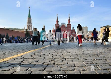 People walking along the Red Square, near Kremlin, the State Historical Museum building on background. Focus on the foreground Stock Photo