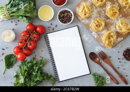 Healthy cooking concept. Recipe notebook and fresh spaghetti ingredients for making Italian pasta on stone background. Top view, flat lay and copy spa Stock Photo