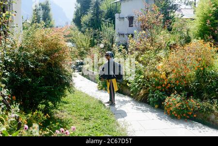 Front View solo woman in hiking sportswear and with a backpack on her shoulders. Sporty woman with backpack walking outdoors. Travel girl stands on ga Stock Photo