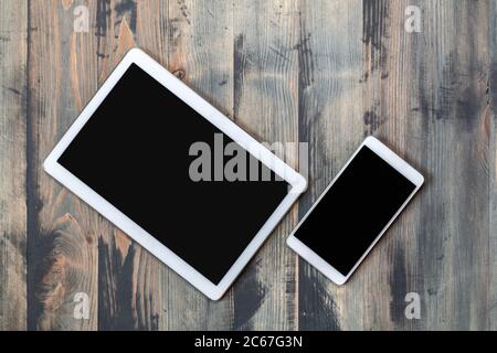 Mobile smartphone and tablet with black screen wooden vintage style background. Top view of modern devices on old wooden background. Flat lay, copy sp Stock Photo