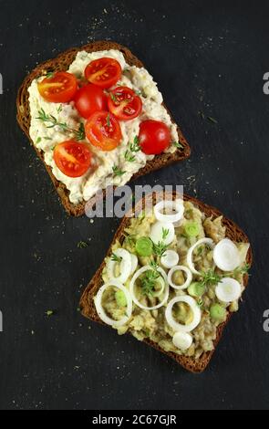 Eggplant salad toast decorated with tomato slices and onion on a dark background. View from above. Stock Photo