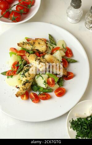 Healthy food concept. Fresh salad with red gurnard fish fillets gratin, asparagus cherry tomatoes, potatoes and herbs. Top view. Stock Photo