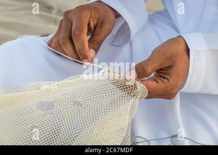 Close up image of the hands of Arabic man weaving fishnet "fishing net" Stock Photo