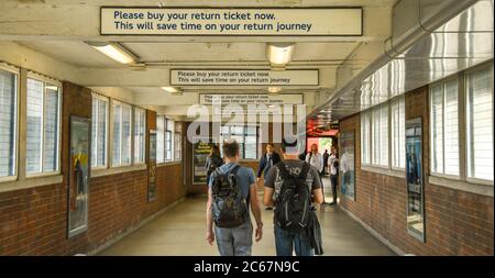 LONDON, ENGLAND - JULY 2018: Two people walking along a corridor from the platform at Wembley underground station in north London Stock Photo