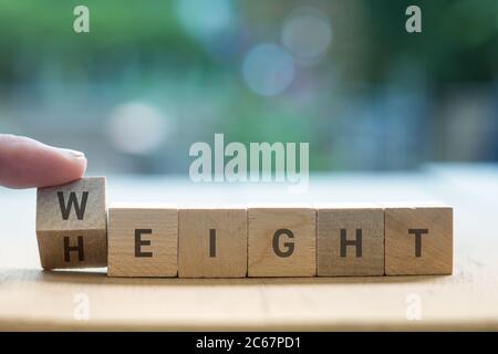 WEIGHT over HEIGHT concept on wood blocks as finger changes W to H Stock Photo