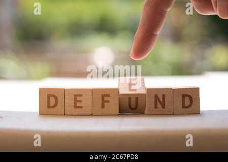 DEFEND DEFUND Police concept on wood blocks as finger changes Stock Photo