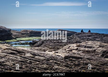 People on rocky Mediterranean Sea coast near famous Pigeon Rock in Beirut, Lebanon Stock Photo