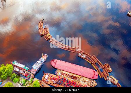 Abstract art industrial background with copy space. Abandoned pier and boats with reflection of sky in the water. Aerial close up drone view. Stock Photo