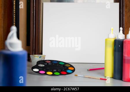 Colourful palette of watercolour paint and brush next to white canvas at artist studio. Creativity and education concept. Nobody, space for text Stock Photo