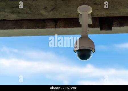 Panoramic security camera hanging on the wall with blue sky background and copy space for text. Surveillance CCTV camera. Nobody Stock Photo
