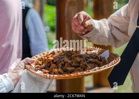 Close up view of hand taking home made rye bread sample in outdoor festival. Organic black bread Stock Photo
