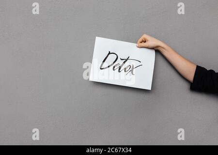 Close up photo of woman hand holding postcard on gray background Stock Photo