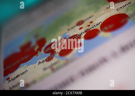 Viersen, Germany - July 7. 2020: Closeup of mobile phone screen with blurred map of world wide distribution of covid-19 infected people (focus on cent Stock Photo