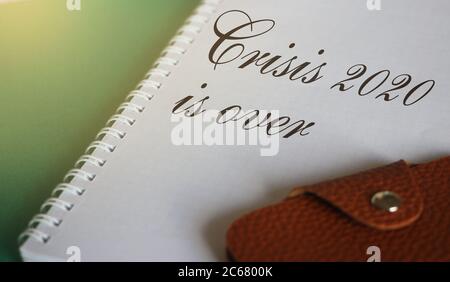Crisis 2020 is Over words on page of copybook and wallet. business concept Stock Photo
