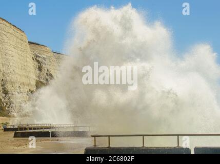 Close by the towering white foamy waves crashing onto the seafront walkway next to the white cliffs Stock Photo