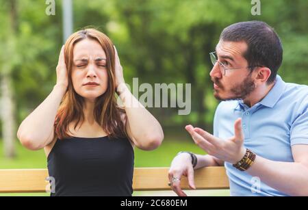 An arguing couple view, man is dictating, woman close ears and unconcerned, doesn't want to hear Stock Photo