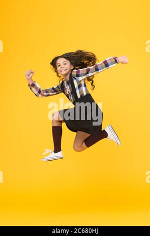 Feel inner energy. Girl with long hair jumping on yellow background. Carefree kid summer holiday. Time for fun. Active girl feel freedom. Fun and jump. Happy childrens day. Jump concept. Break into. Stock Photo