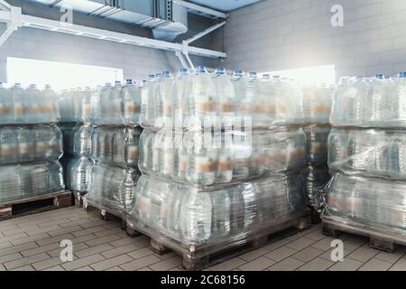 Plastic bottles with a drink on pallets in warehouse ready for transportation to stores for sale. Stock Photo
