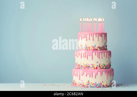 Tiered birthday cake with drip frosting and twelve candles Stock Photo