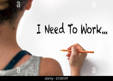 Female hand writting the phrase I Need To Work on a white paper, indoors. Lockdown jobs crisis concept Stock Photo