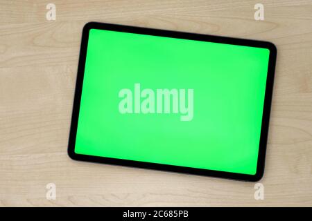 Top view of green screen tablet device on patterned wooden table Stock Photo