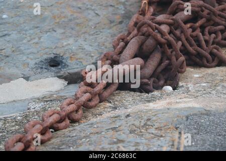 Close up of a rusty chain lying on the dockside  Stock Photo
