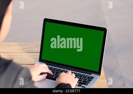 over should of woman using green screen laptop computer on sunny day. blur background Stock Photo