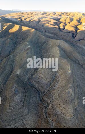 An aerial view shows the rugged, eroded desert landscape that surrounds Las Vegas, Nevada. This desert area averages over 95 degrees F during summer. Stock Photo