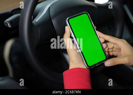 close up one man holding green screen phone inside car. blurred steering wheel background Stock Photo