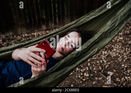 Teen girl laying in hammock playing on cell phone Stock Photo