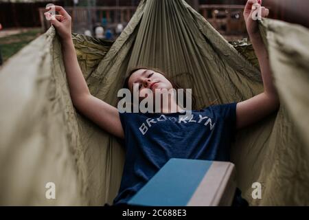 Teen girl laying in hammock with a book Stock Photo