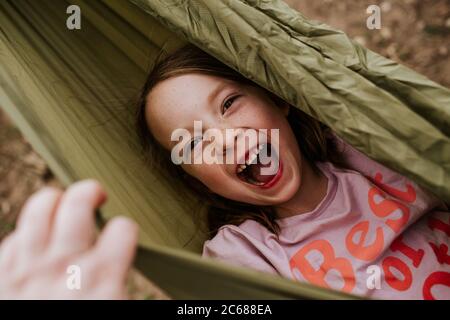 Overhead of silly girl laughing in hammock Stock Photo
