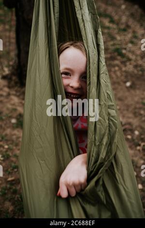 Vertical of young girl wrapped up in hammock outside Stock Photo
