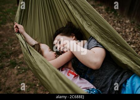 Young girls laying in hammock smiling at each other Stock Photo
