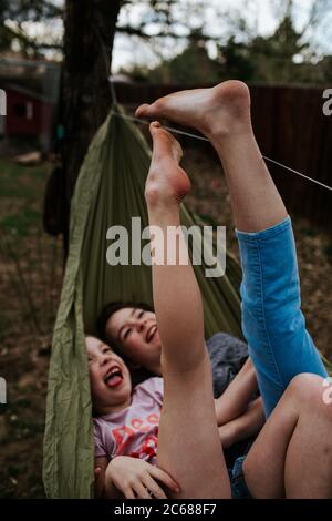 Young girls laying in hammock playing with feet Stock Photo