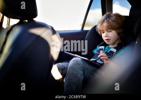 Cute boy using tablet PC while traveling in car Stock Photo