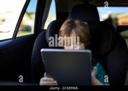 Boy using digital tablet while traveling in car Stock Photo