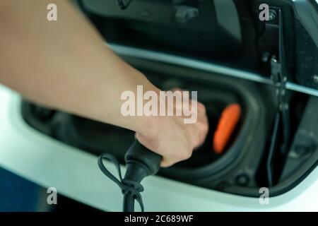 young man plugging in his electric vehicle Stock Photo
