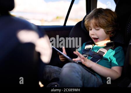 Cute boy using digital tablet while sitting in car Stock Photo