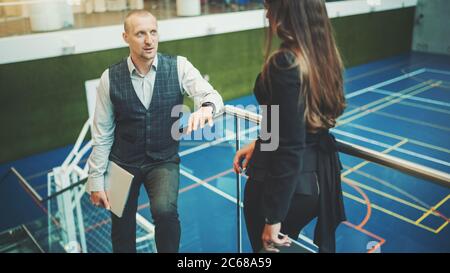 A lively conversation between two business partners with selective focus on a man entrepreneur with a laptop talking to his female colleague Stock Photo
