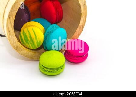 Sweet and colourful french macaroons or macaron stack in bucket wooden isolated on white background. Stock Photo