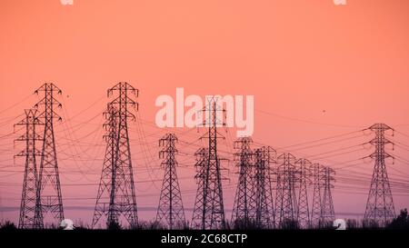 Sunset view of high voltage electricity towers on the shoreline of San Francisco bay area; California Stock Photo