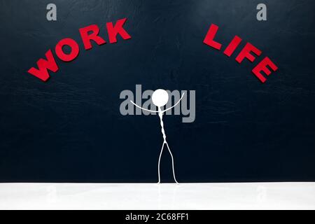 Work-life balance concept. Human stick figure balancing a red seesaw with work and life word cutout.