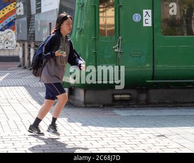 Young Japanese school children walking in a line holding hands in Ueno ...