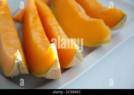 High angle view of orange melon sliced on the plate against a white background Stock Photo